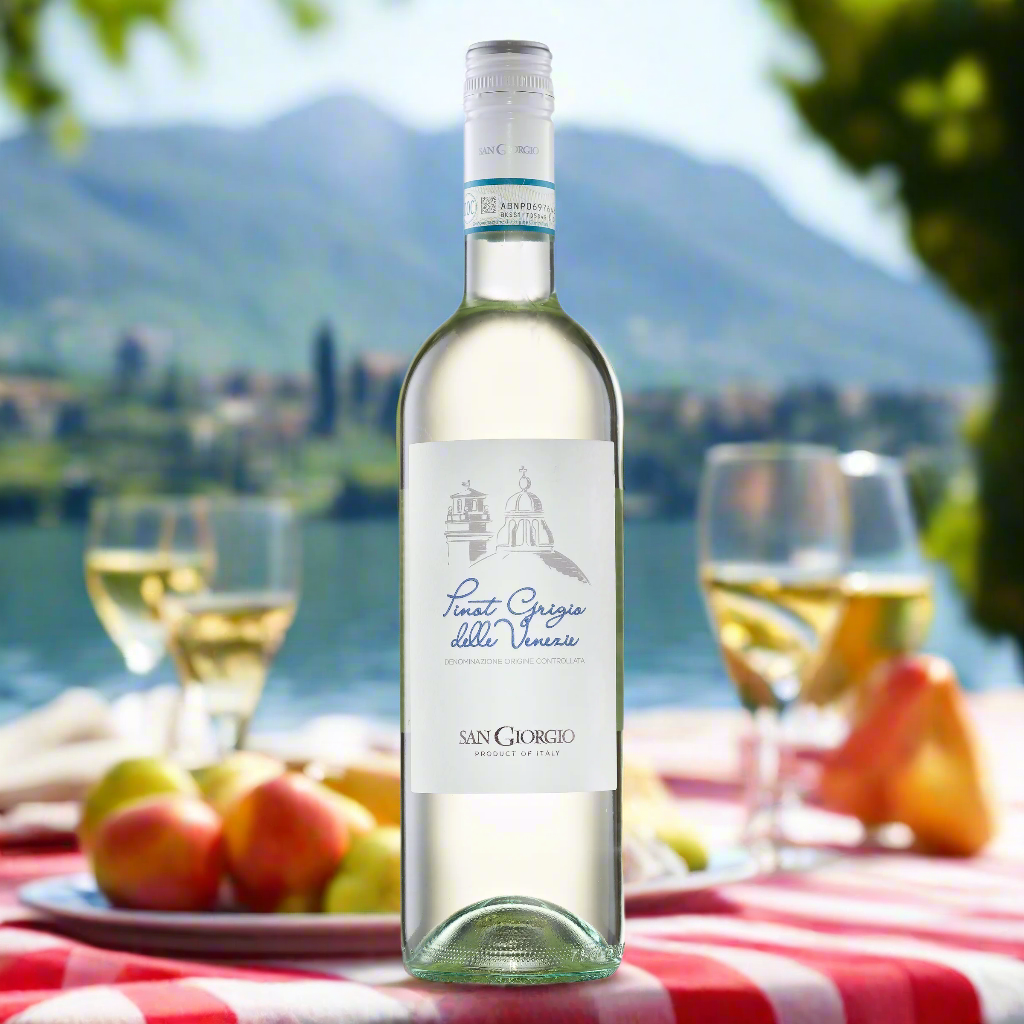 A breezy picnic scene by Lake Garda—think checkered blanket, fresh fruit, light cheeses, and a chilled bottle of Pinot Grigio. Soft reflections on the water and alpine hills in the distance add a refreshing, summery feel.