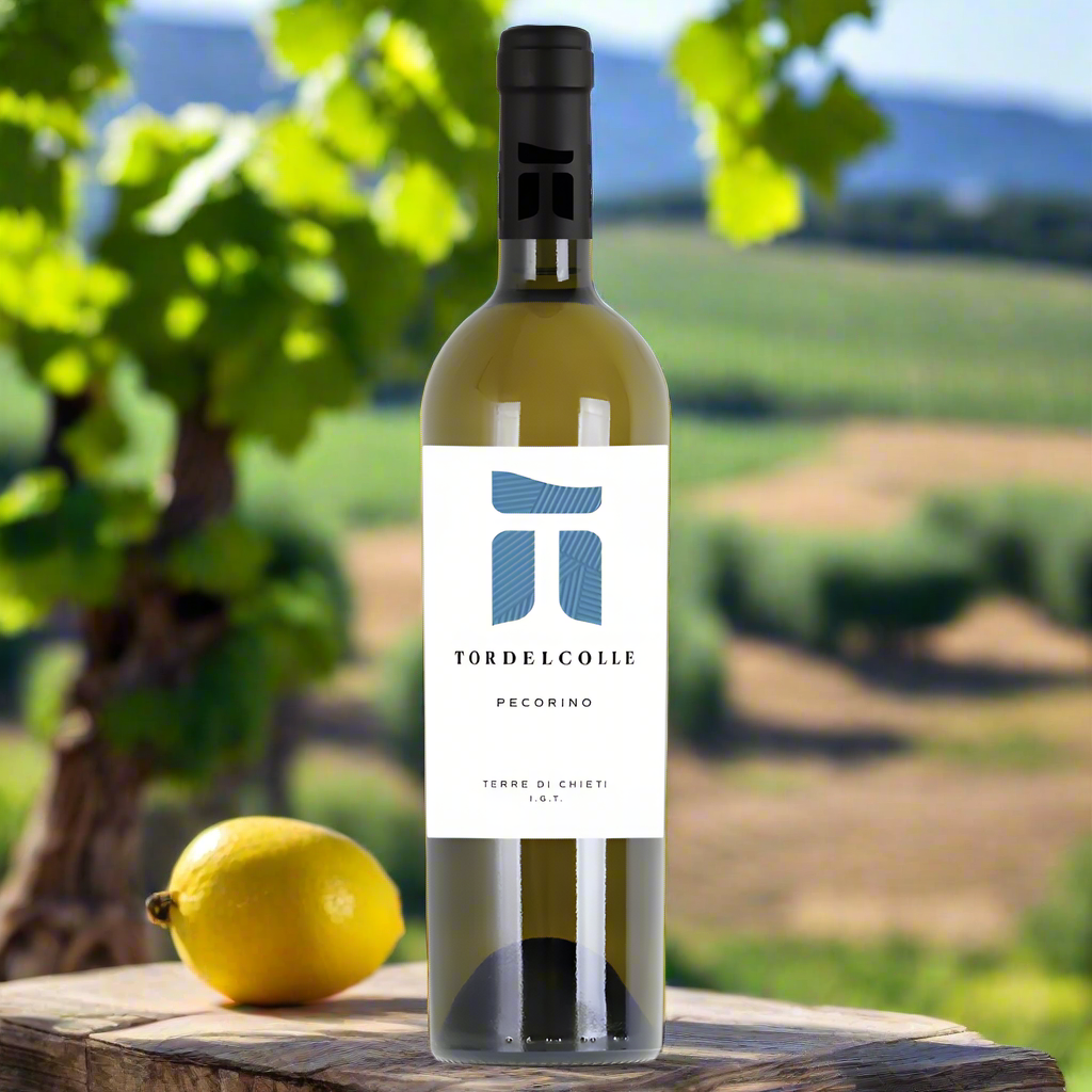 Tor del Colle Pecorino Terre di Chieti bottle on vineyard table with lemons and herbs.