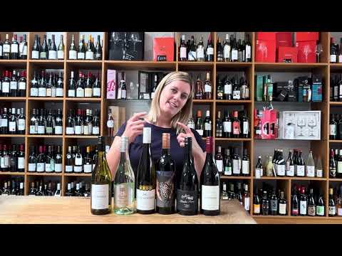 Unboxing a curated case of Australian and New Zealand wines, featuring red and white bottles on a wooden counter.